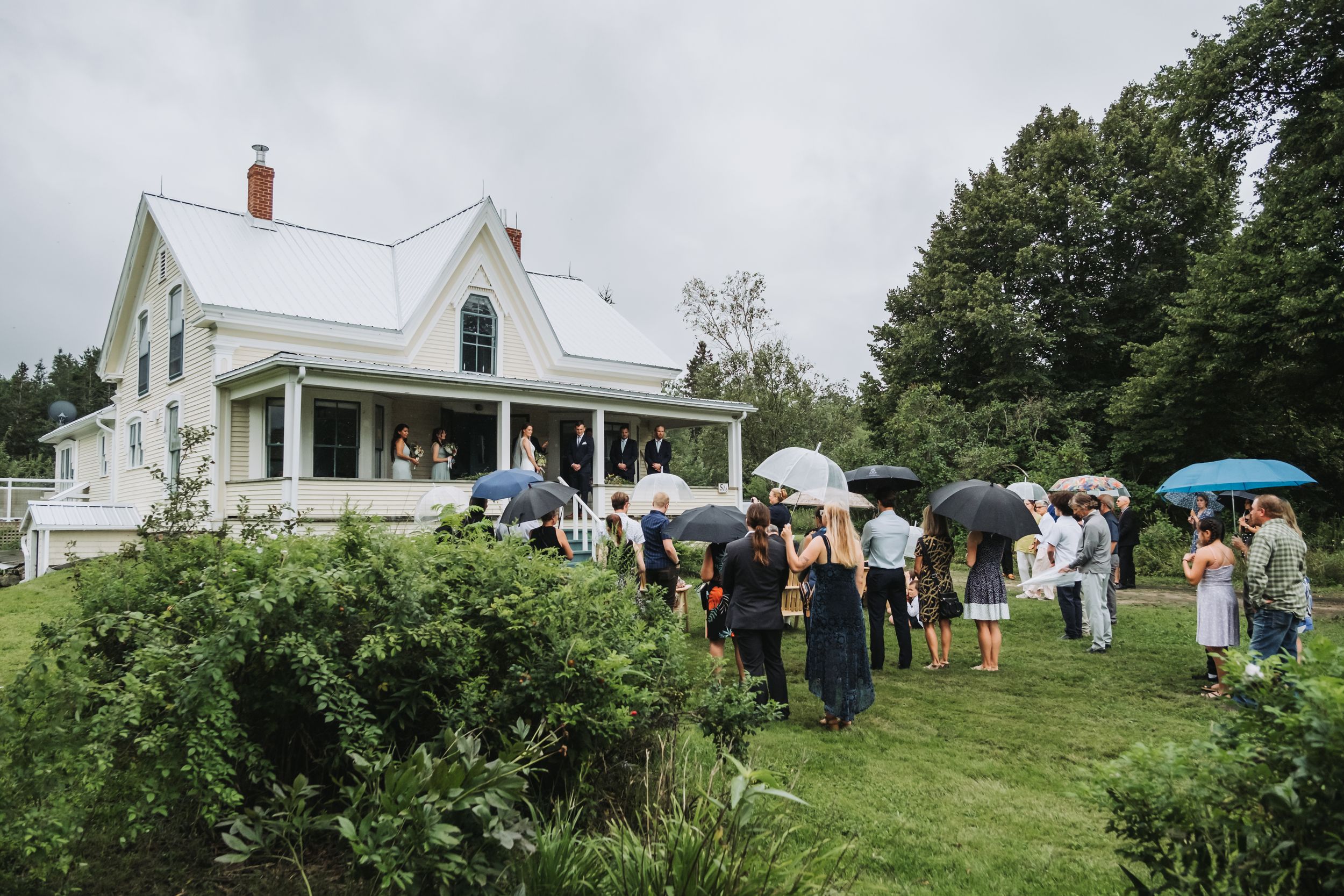 Wedding ceremony on the front porch of a house on a rainy day in Nova Scotia.