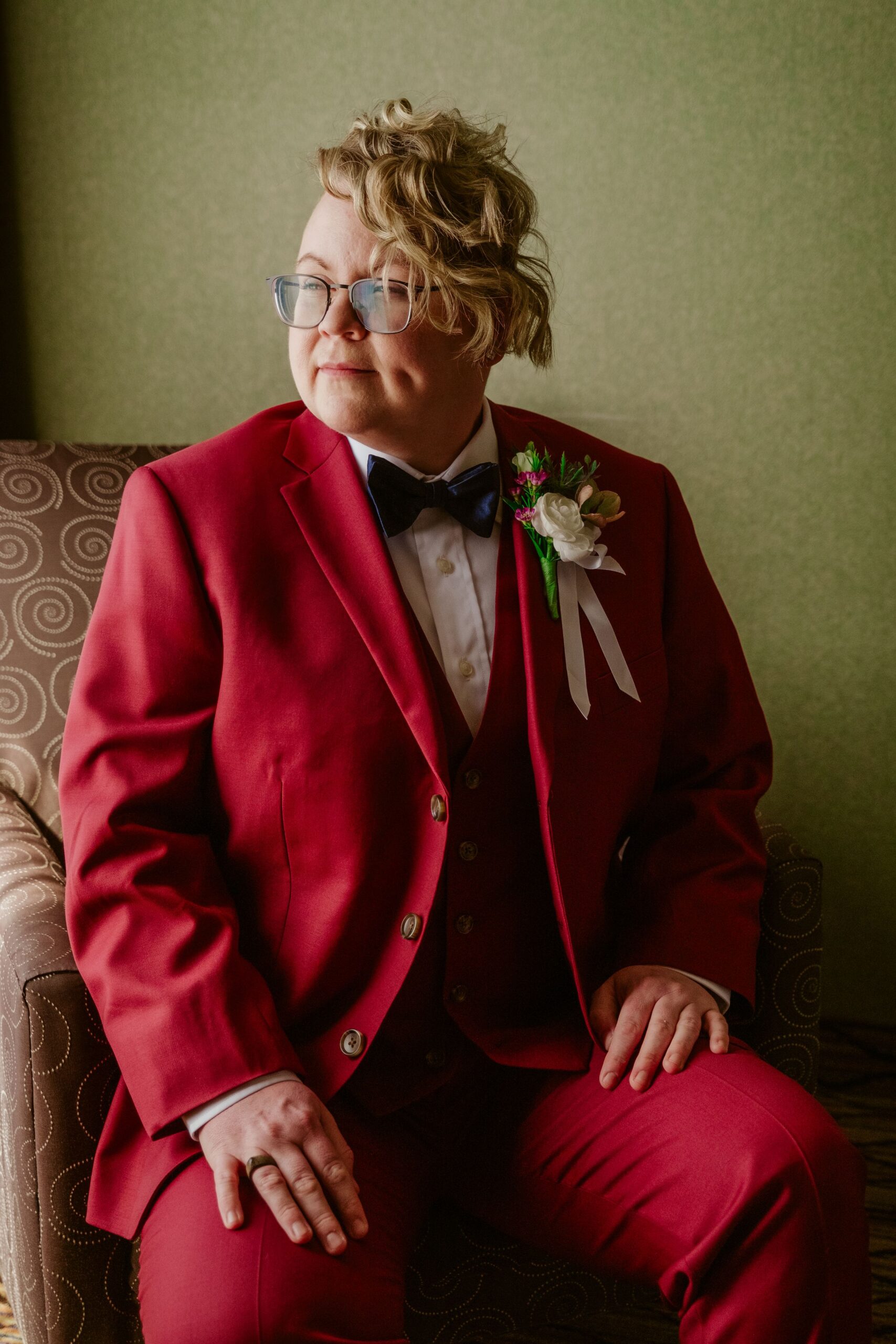 Queer person wearing red suit on wedding day.