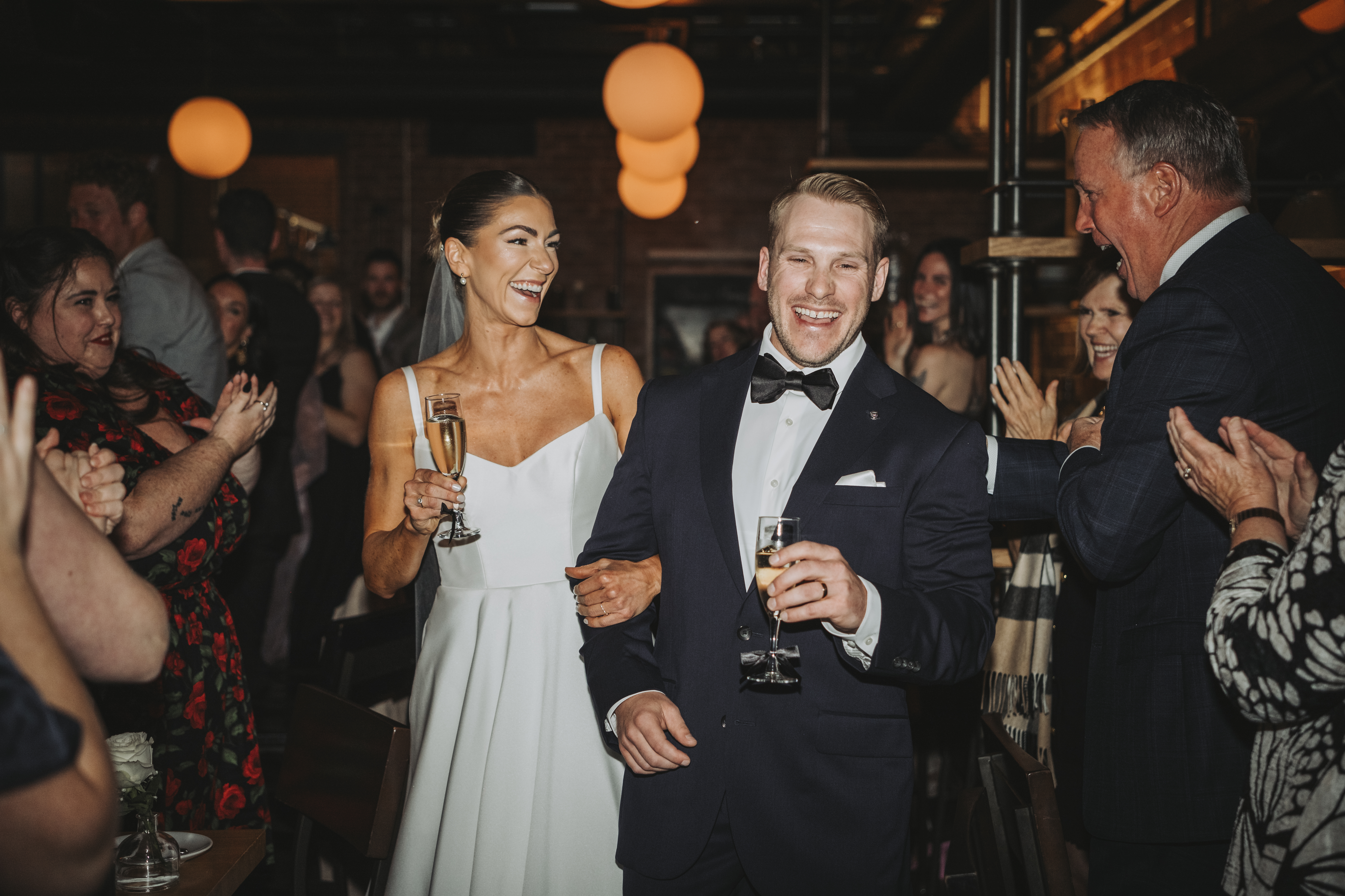 Bride and Groom smile as they exit their wedding ceremony surrounding by cheering guests.